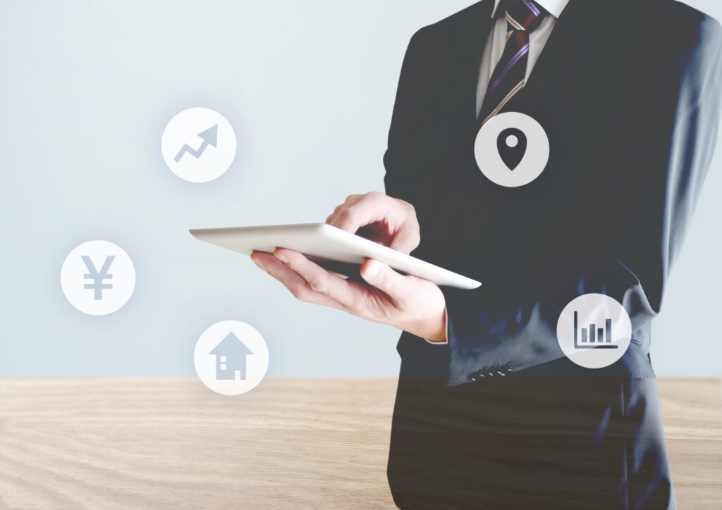 タブレットを持つ男性と不動産アイコン